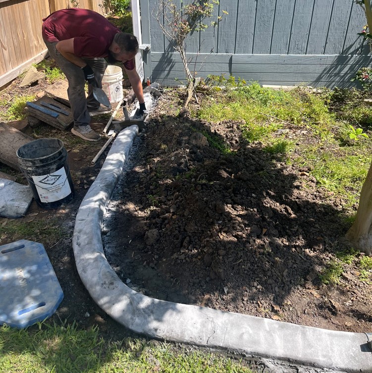 A worker colors a concrete brick used in a landscape curb.